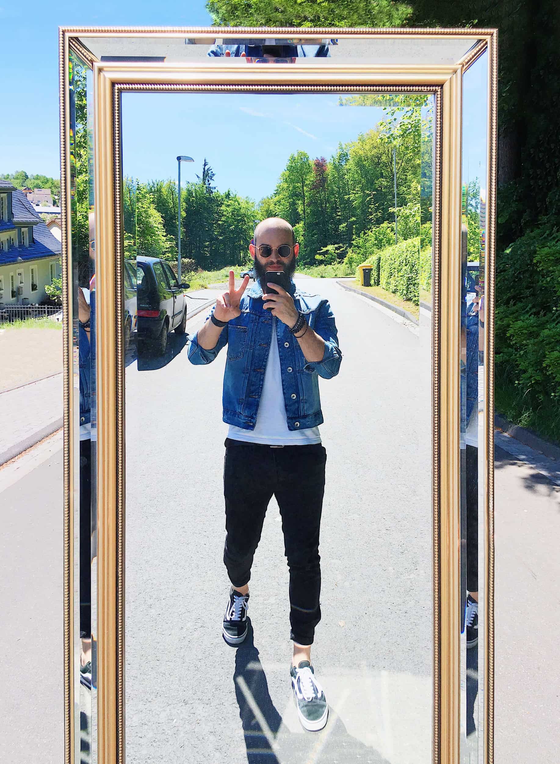 Mann fotografiert sich im Spiegel auf der Straße, Symbol für Selbstbefragung und ehrliche Reflexion im KI-Kontext.
