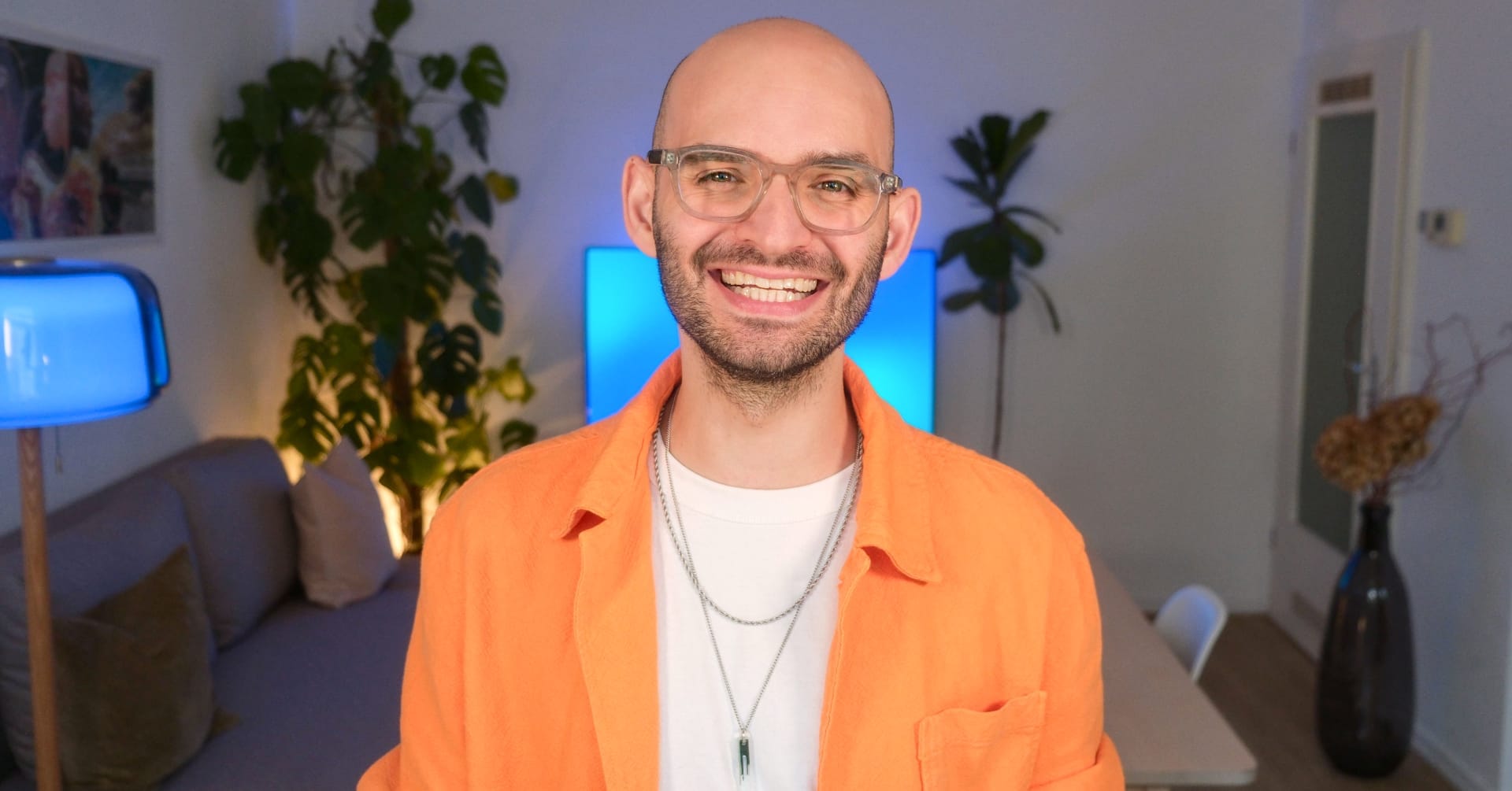 Christos Stavrou lacht in seiner Studioumgebung – Szene aus „KI ✺ Kreative Intelligenz“, Episode 8 über Positionierung und kreatives Denken.