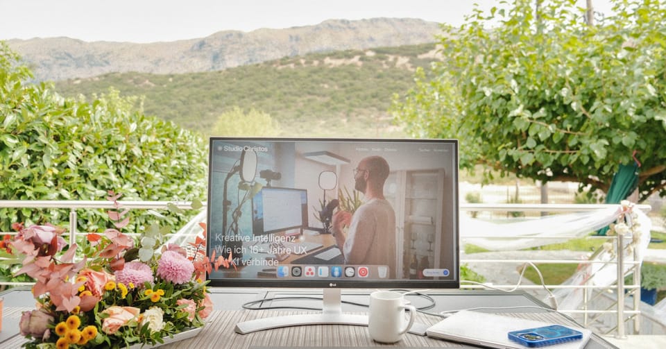 Arbeitsplatz mit Bergblick für den August-Recap. Am Monitor: "Kreative Intelligenz – Wie ich 16+ Jahre UX verbinde"